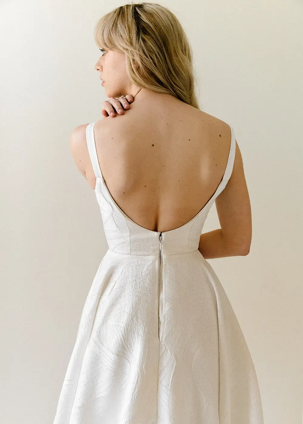 Model is wearing a romantic scoop neck and back wedding dress made from textured jacquard fabric 