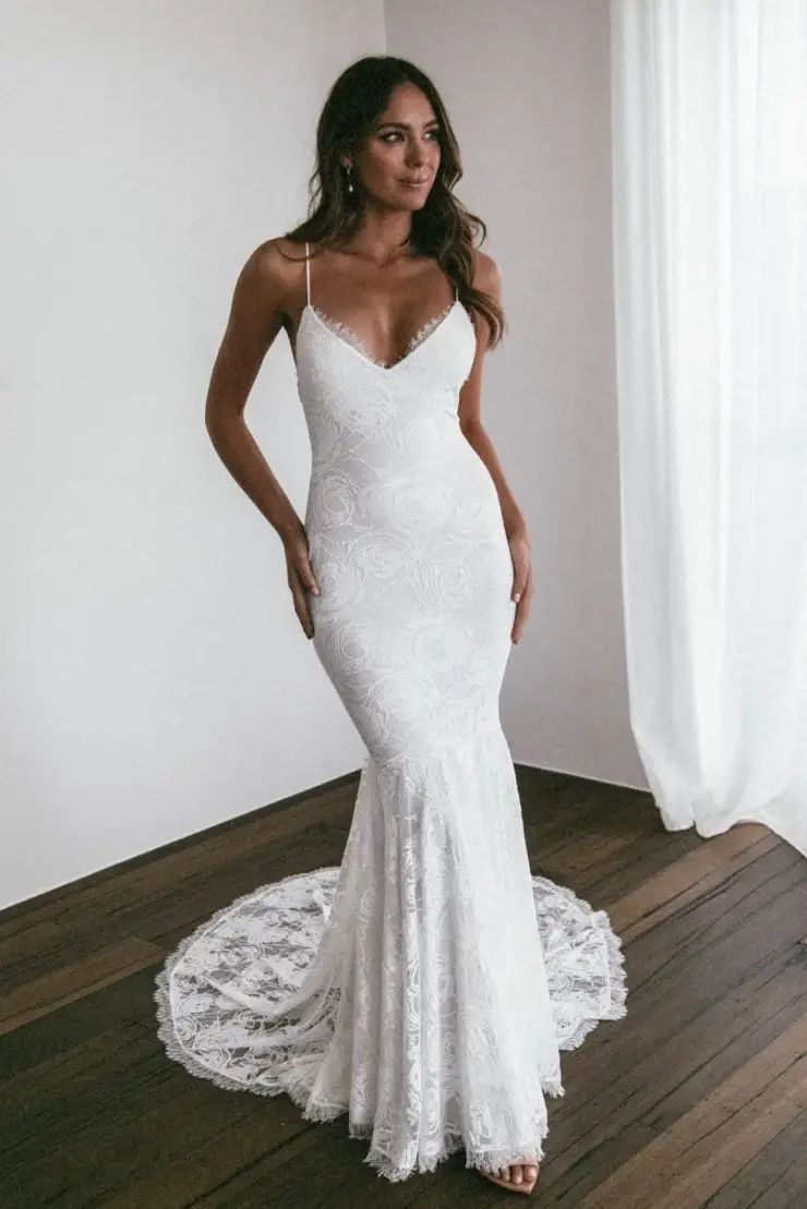model is wearing a sleeveless fit and flare lace wedding dress with spaghetti straps