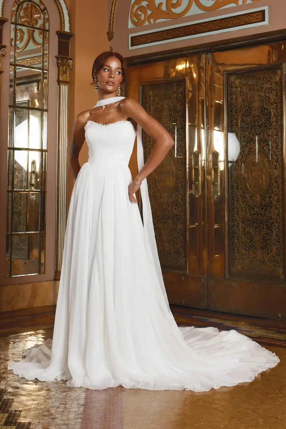 model is wearing a strapless wedding gown with a bridal scarf