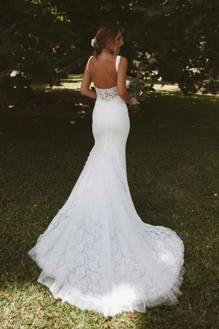 model is wearing an open back lace fit and flare wedding gown