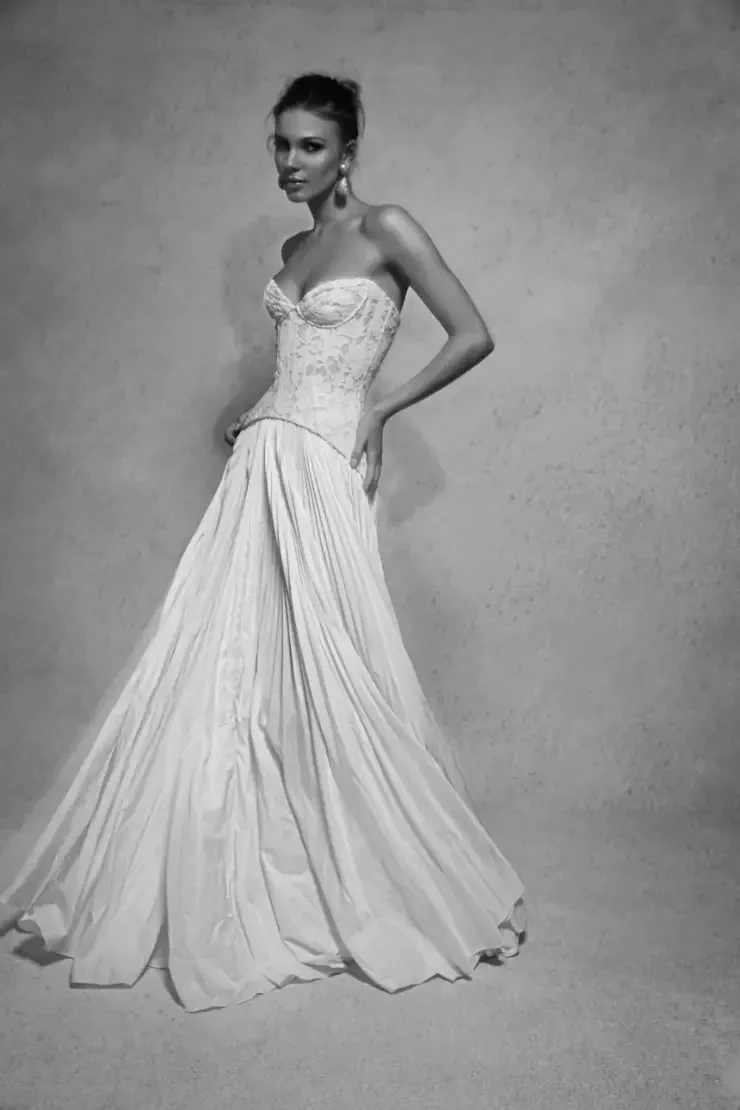 Model is wearing a pleated bridal skirt with a structured corset top with a drop waist